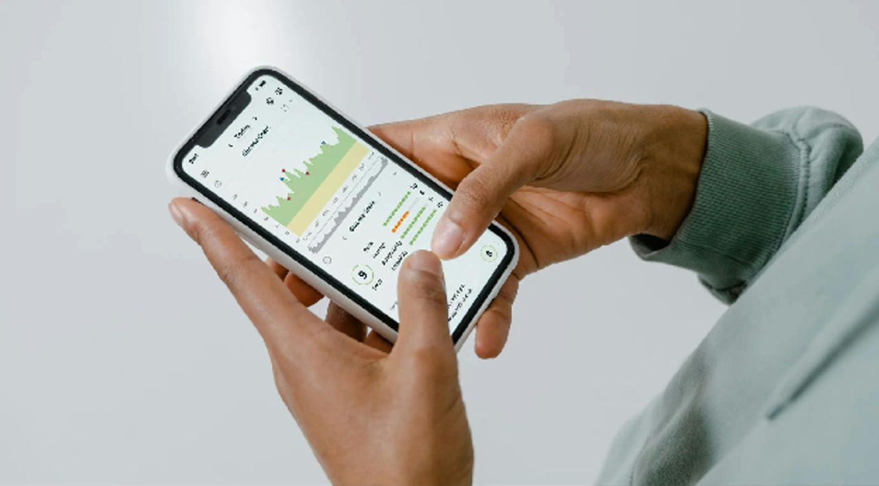 Person holding a smartphone displaying a health app with a glucose chart, showcasing how to track health habits.